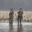 An image of two hunters walking in water. 