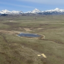 aerial view of a landscape with mountains and grasslands and a lake