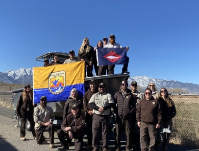 FWS staff on and around boat on trailer on land hold FWS flag, fish pennant 