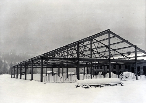 Black and white photo of the frame of a large building in snow.