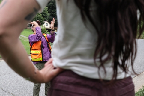 A woman gesturing with her hands, framed by the bent arm of another woman