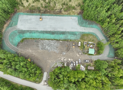 Aerial nadir view of a parking lot with tall woodland surrounding it. 