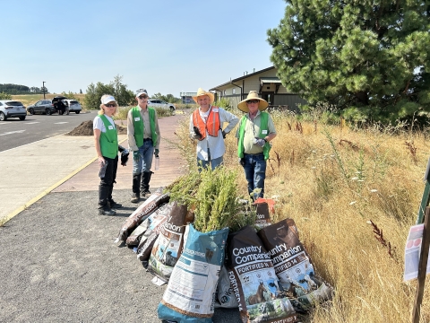 Volunteers in front of bags of weeds they removed