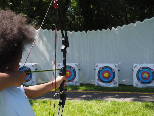 A child points a bow to a target. 