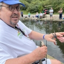Man holding fish and fishing pole by stream