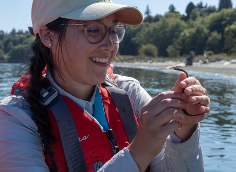 Service intern smiles while holding up a Bay Pipefish. 