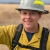 A close up of a person wearing firefighting gear looking at the camera