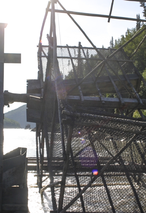 man standing on a fish wheel platform in a large river