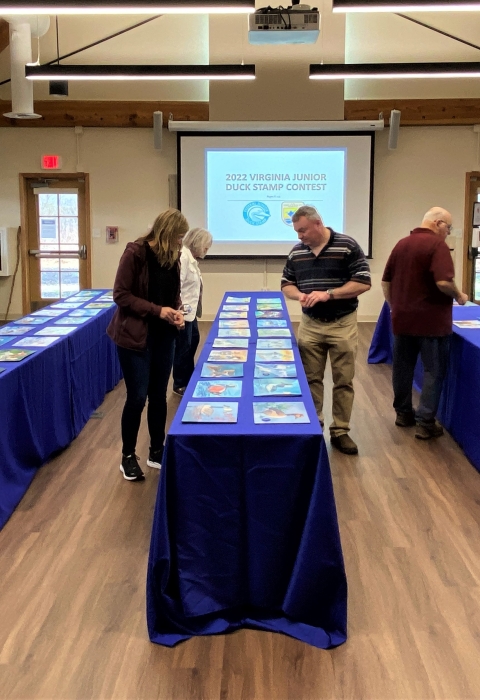 Judges reviewing artwork laid out on tables. 
