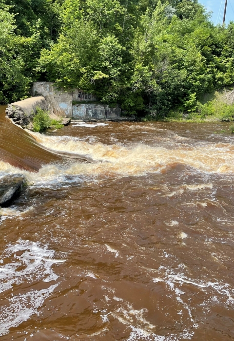 a breached dam with river water flowing through the gap