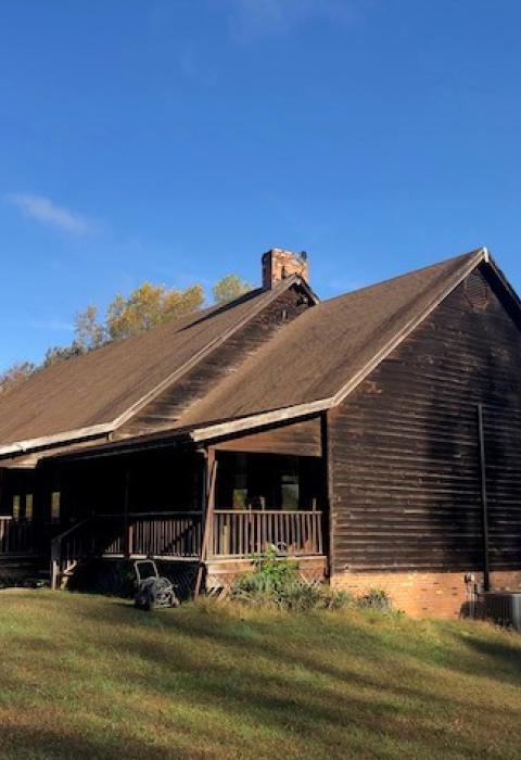 a brown lodge structure with steep roof on a grassy hill 