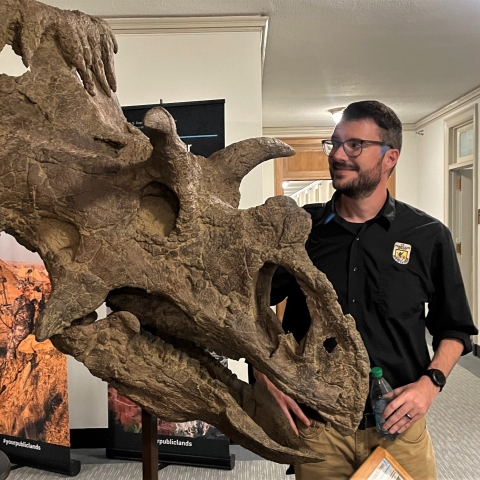 Biologist stands next to a triceratops skull