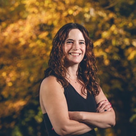 a woman smiles with her arms crossed
