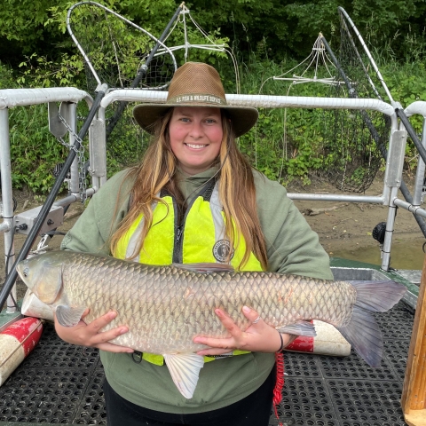 Haley on a boat holding a 3 foot long grass carp