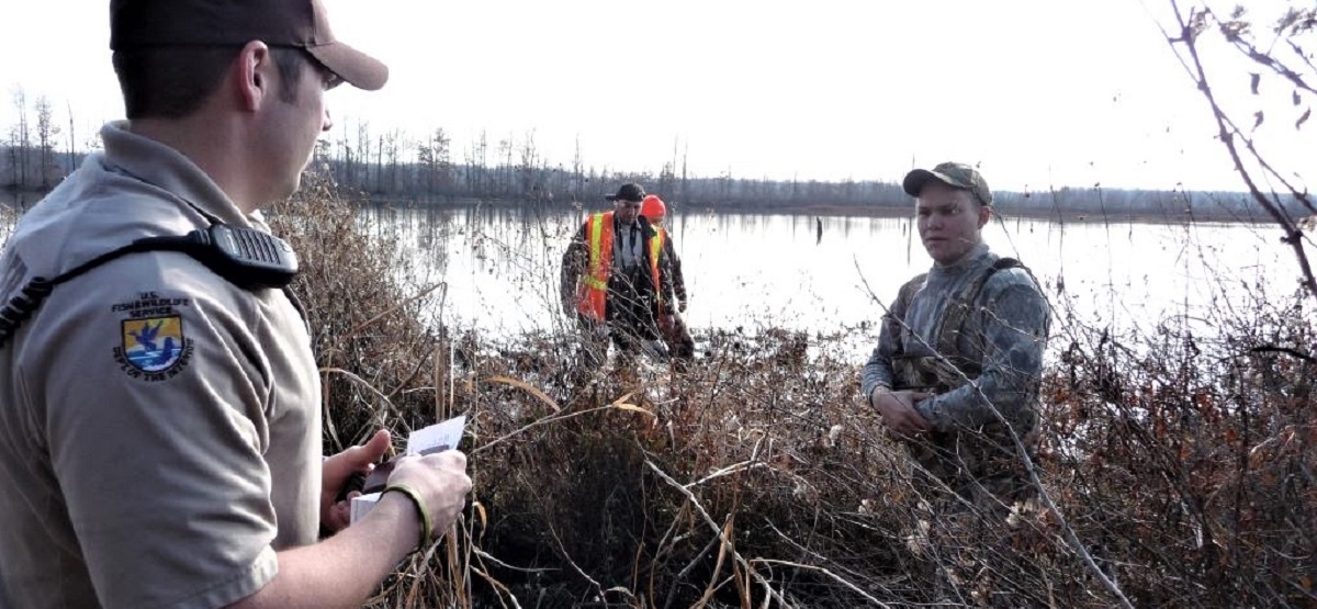 Law enforcement officer talking with hunters on lake