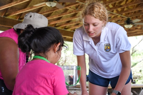 A child and a FWS education intern look at a butterfly