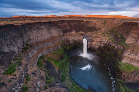 A waterfall plunges over a canyon wall into a pool