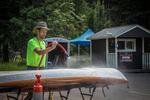 A person sprays off the bottom of a boat.