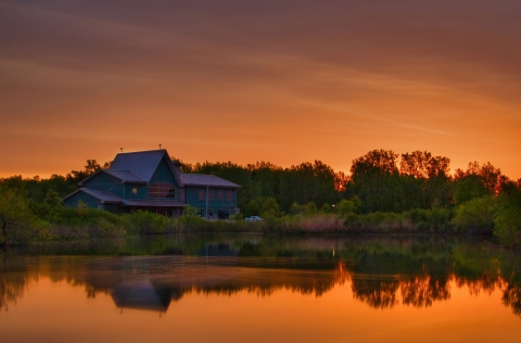 Large green building with sunrise reflected in the water