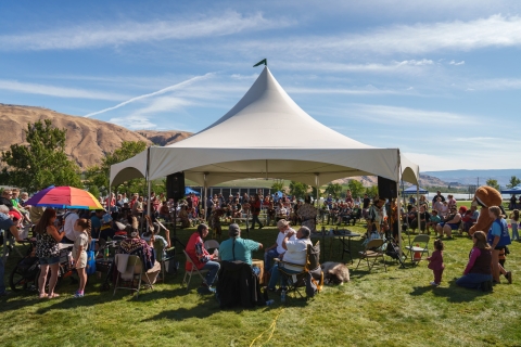 a white tent over powwow dancers surrounded by a crowd