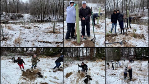 Volunteers pose for pictures with their newly-planted trees and shrubs.