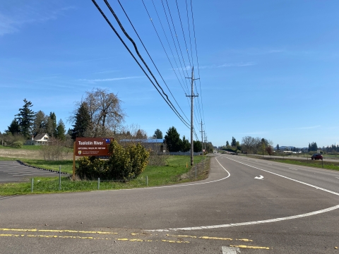 Image of a dark gray asphalt turn lane with white striping and a brown entrance sign for the refuge.