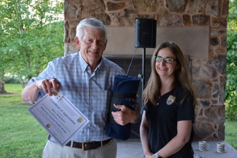 Smiling man holding an award certificate alongside a woman smiling.