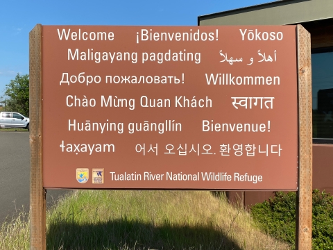 image of a large brown sign with white lettering that says the word welcome in several languages.