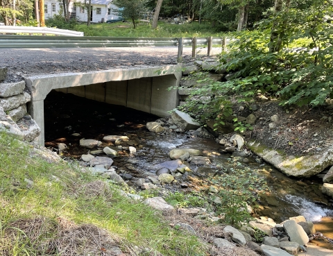 A photo of a stream flowing under a road through a new culvert