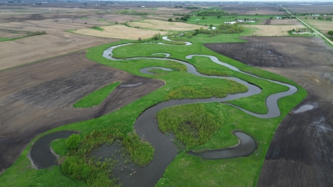 An aerial landscape image showing small, interconnected, crescent‑shaped wetlands surrounded by lush green vegetation.