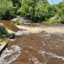 a breached dam with river water flowing through the gap