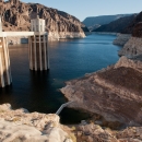 Image of a lake surrounded by geologic rock formations, with 2 cylindrical structures 