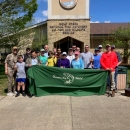 Group of people posing with fishing poles and banner