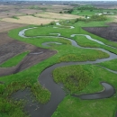 An aerial landscape image showing small, interconnected, crescent‑shaped wetlands surrounded by lush green vegetation.