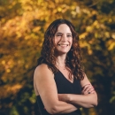a woman smiles with her arms crossed