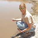 woman kneeling beside pond and smiling