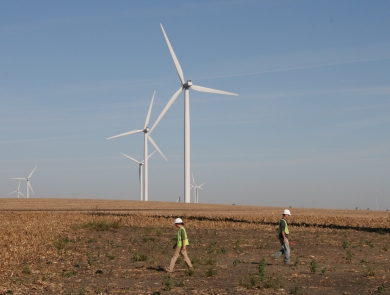 People searching a plot around a wind turbine with wind turbines in the background.