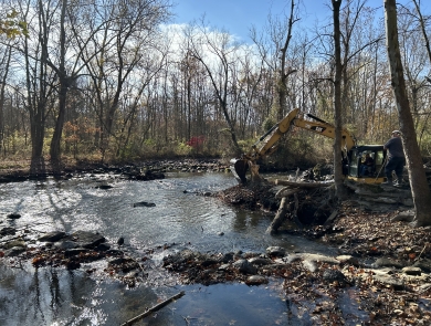 An excavator removing remnants of a dam from a river