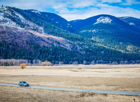 A car drives along riverside road at Kootenai NWR