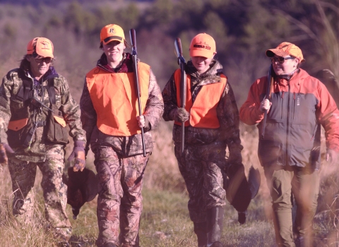 Four hunters in blaze orange walking after a pheasant hunt 