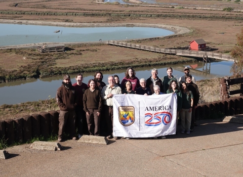 FWS staff poses with America 250 flag in front of wetland