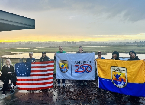 8 people in front of wetland holding 3 flags, Betsy Ross US flag at left