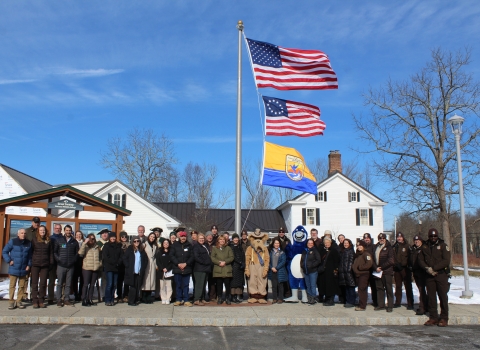 people pose at flagpole, under 2 US flags, USFWS one