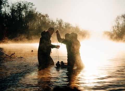 Waterfowl hunters in waders set up duck decoys in a North Carolina Wetland